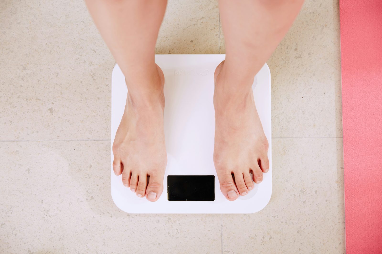 Person standing on a bathroom scale, representing BMI and body fat percentage measurement