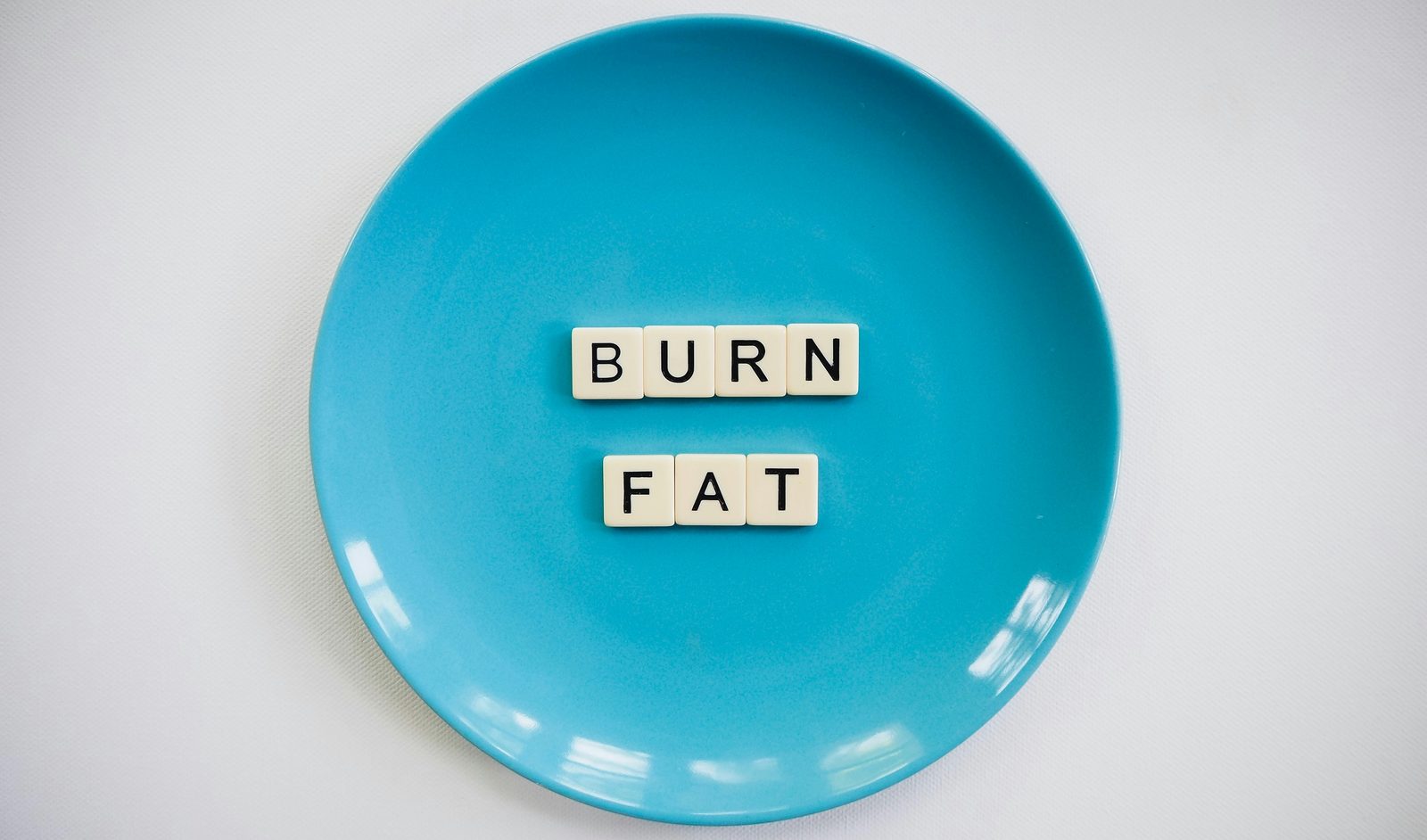 Blue plate with scrabble tiles spelling BURN FAT