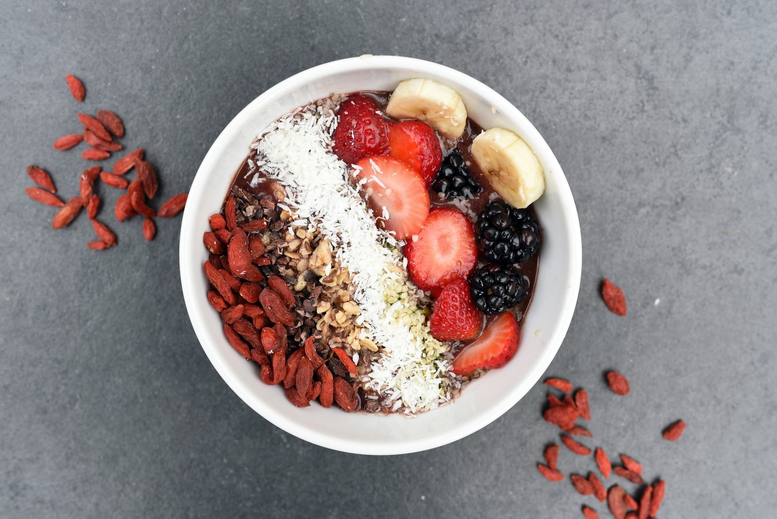 Acai bowl topped with berries, goji berries, banana, and nuts